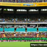 짐바브웨에서 축구 경기 관람하기 - **Vibrant Zimbabwean Football Stadium Atmosphere:**
    A panoramic, high-angle shot capturing the e...